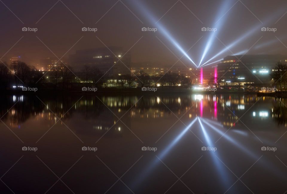 Helsinki, Finland - January 6, 2020: Light beams from light installation Lyyra in Kallion virastotalo building reflected from the Baltic sea in Hakaniemi district of Helsinki during Lux Helsinki 2020 light arts festival on extremely thick fog weather