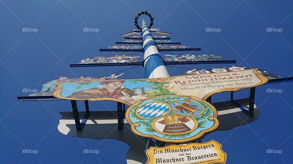 Maibäume are giant stakes, located in the center of the towns painted white and blue (the colors of the Bavarian flag) and decorated with wooden silhouettes representing the craftsmen and traditional professionals of the city. Munich, Germany.