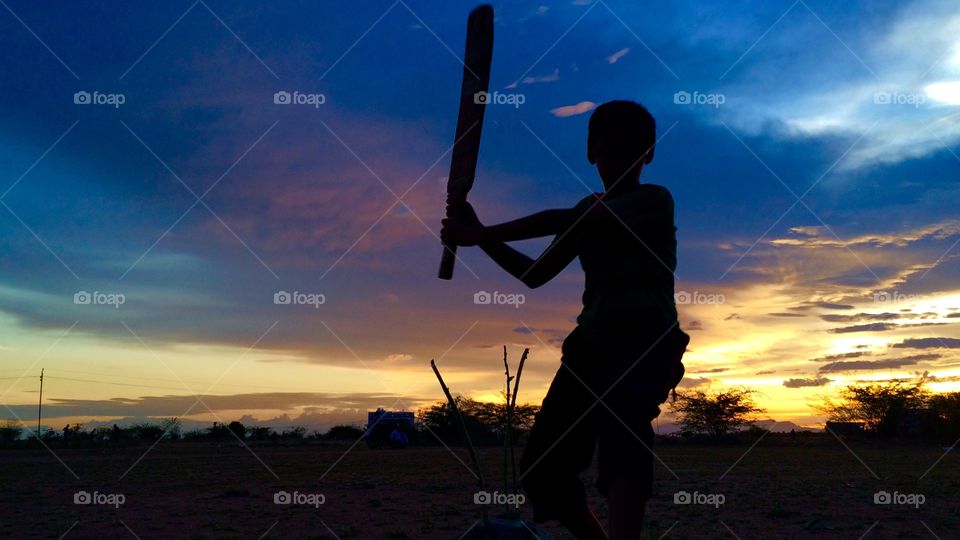 Silhouette of boy with bat