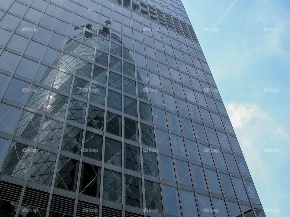 The Gherkin in London reflected in another office building on a clear day