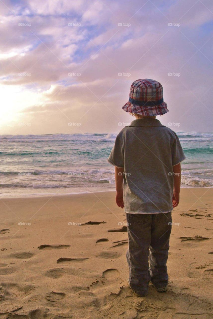 boy on the beach looking at the ocean