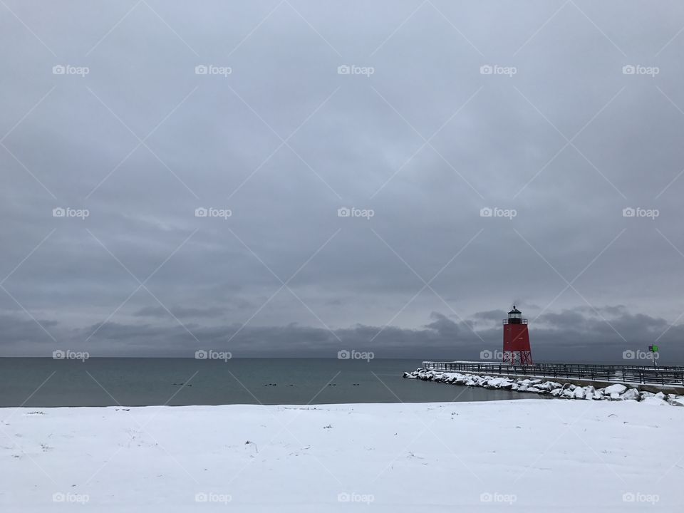 Cold gray snow covered morning at the breakwall on Lake Michigan in Charlevoix Michigan 