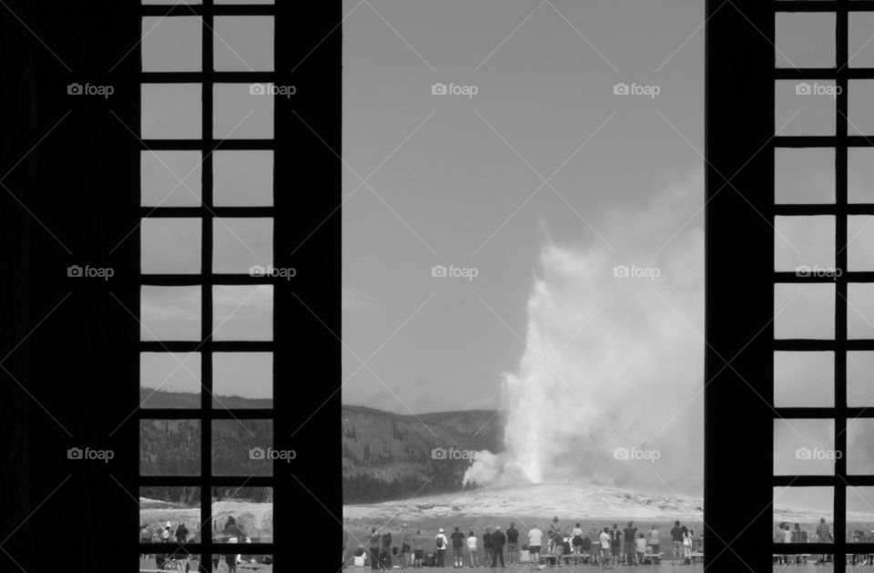 Old Faithful through a window. Old Faithful erupting viewed  through the window inside the lodge.