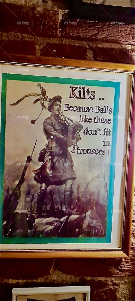 „KILTs - because balls these big don’t fit in trousers“ says the self explanatory sign picturing a Scottish bag pipe player who is wearing - what else ??? - naturally a KILT. 2022. Hypnotic Productions