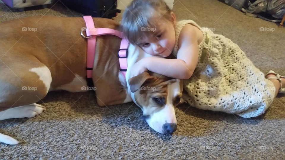 A little girl hugging her dog at home