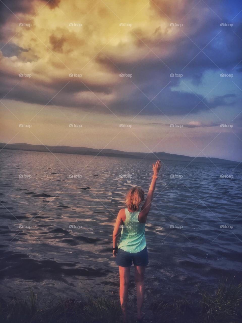 девушка стоит спиной к озеру