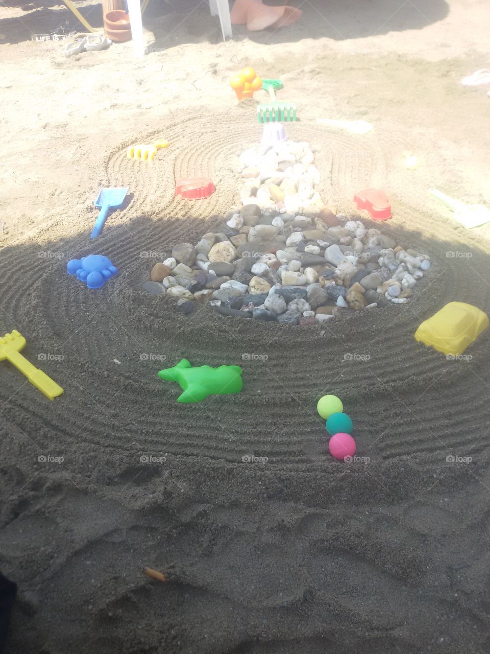 Kid toys and tree rock in sand