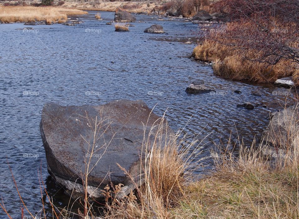 A large boulder on the banks of the Crooked River in a canyon in Central Oregon. 