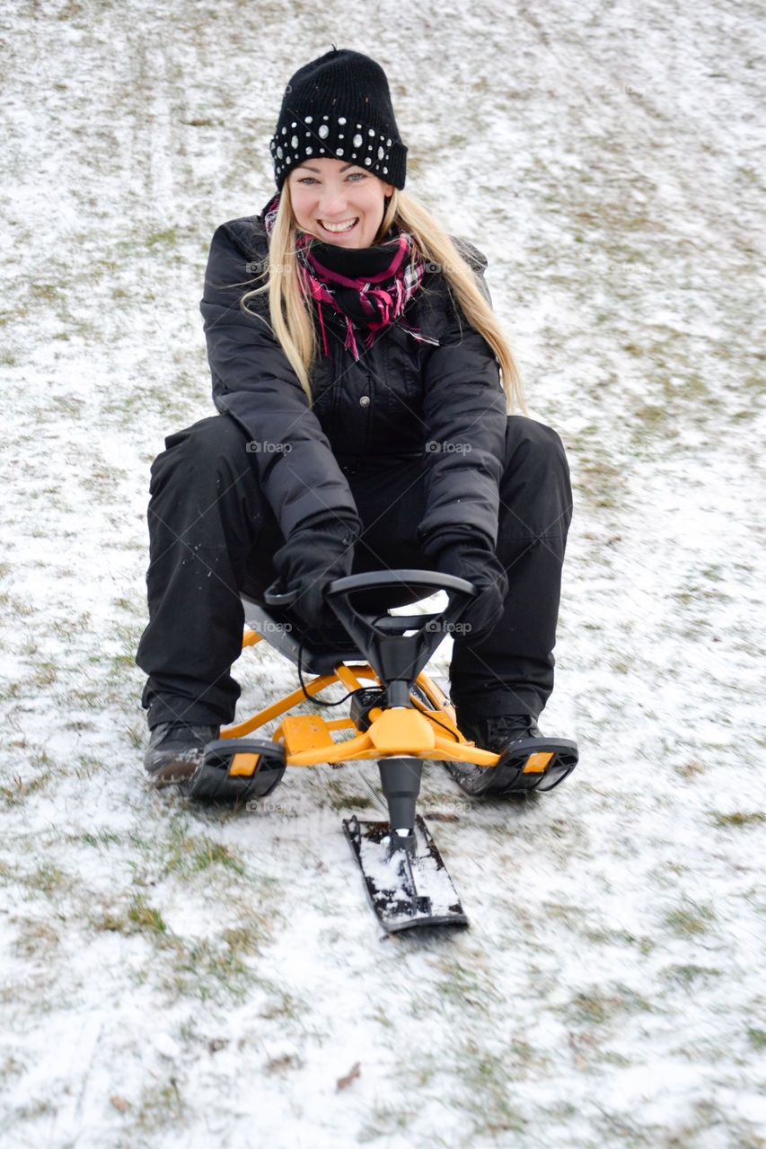 A woman of 30 years of age go sledding in the snow.