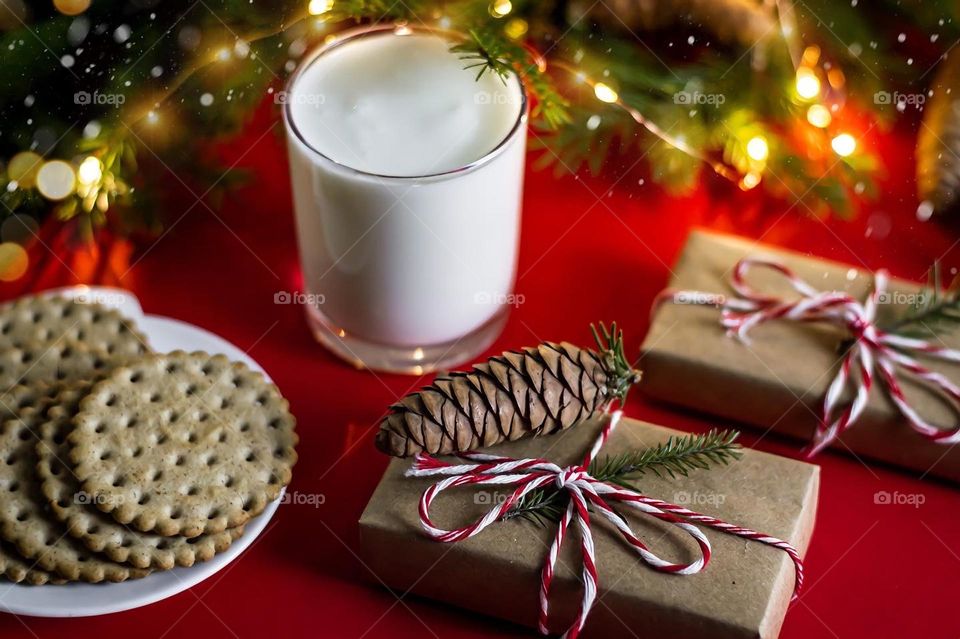 Food still life New Year's drink, milk in a glass cup, craft gifts and cookies on a red background