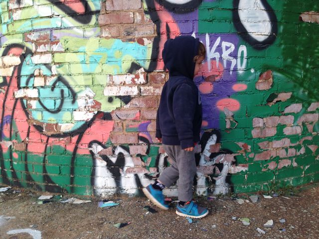 Three-year-old boy walking by graffiti.