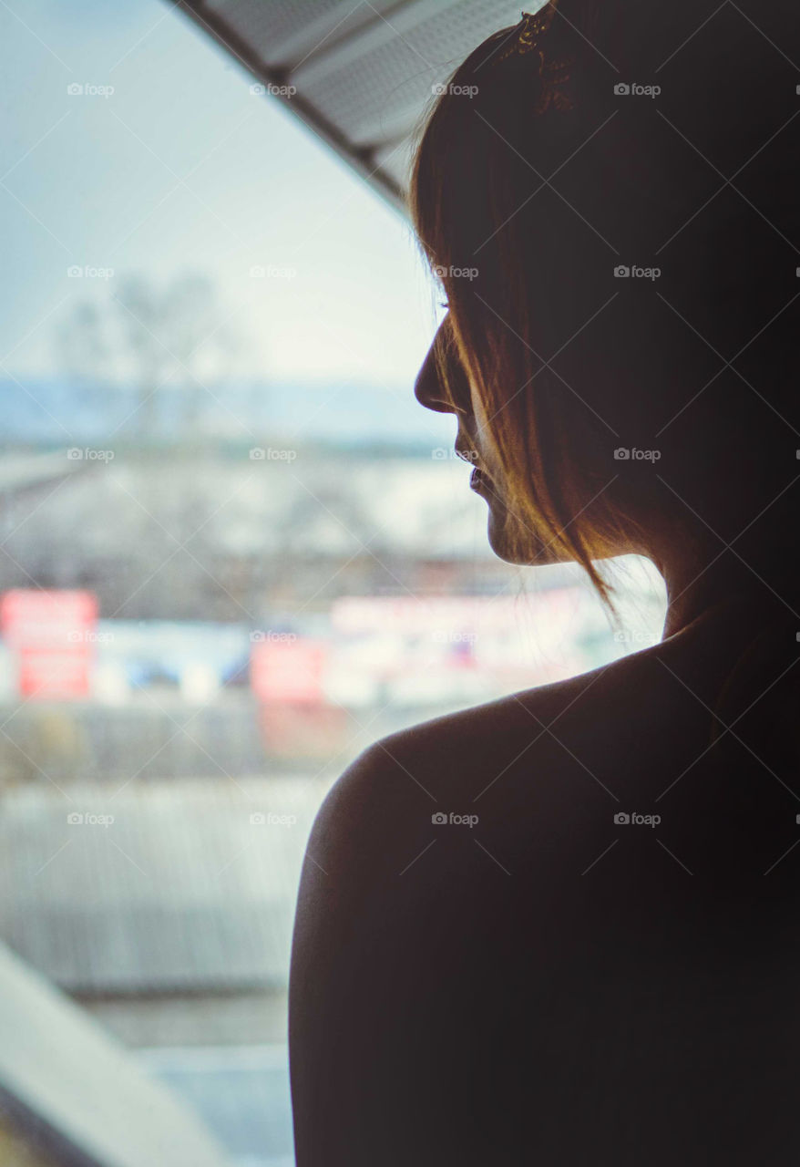 Beautiful girl is staying near a window