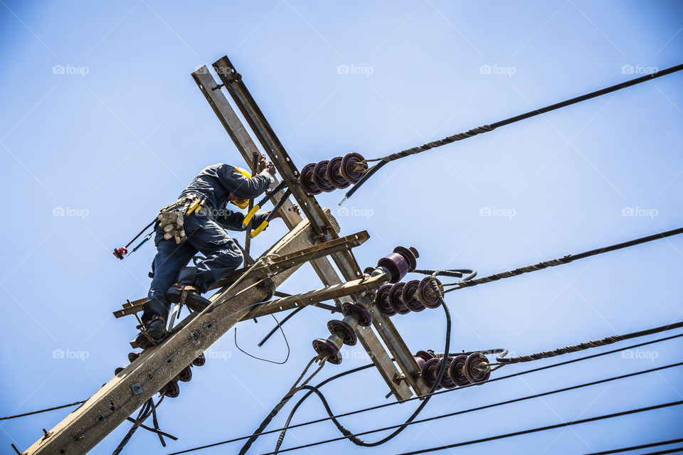 Electrician working on the electricity pole to replace the electrical insulator