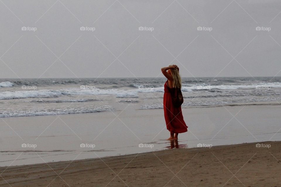 The a woman is enjoying the sunset while taking a walk on the seashore.She looks lost in the beauty of nature and just loving the movement without anybody cares or not. 