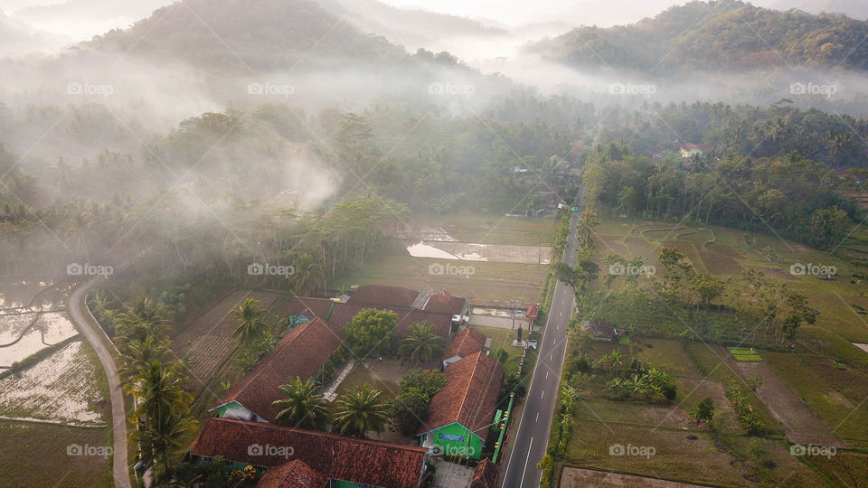 Magical golden hour aerial hidden village rice field, hills and mist purwerejo indonesia