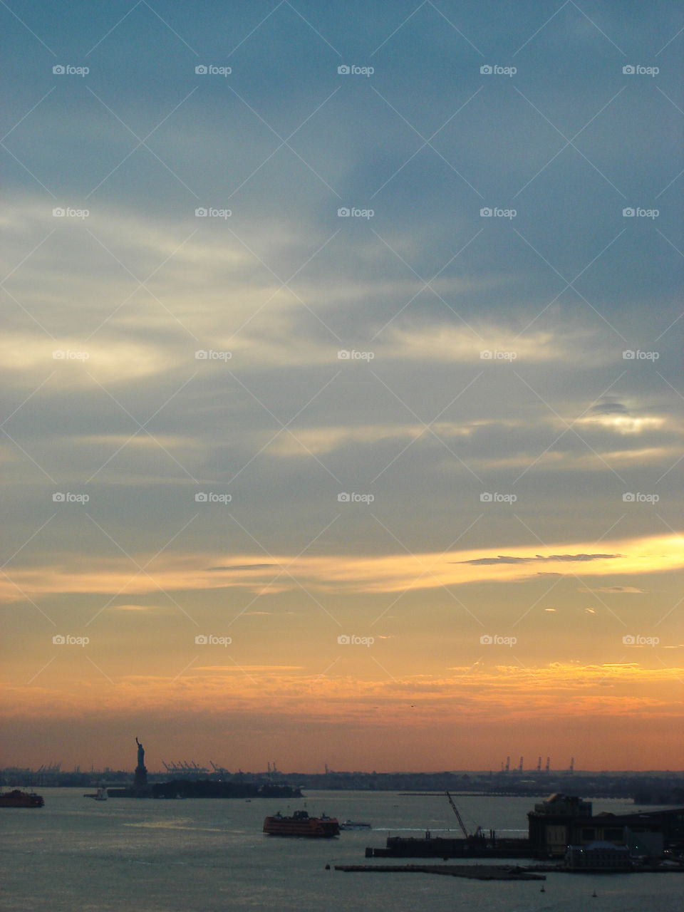 Dusk on the Hudson River. With the silhouette of the statue of Liberty on the horizon..