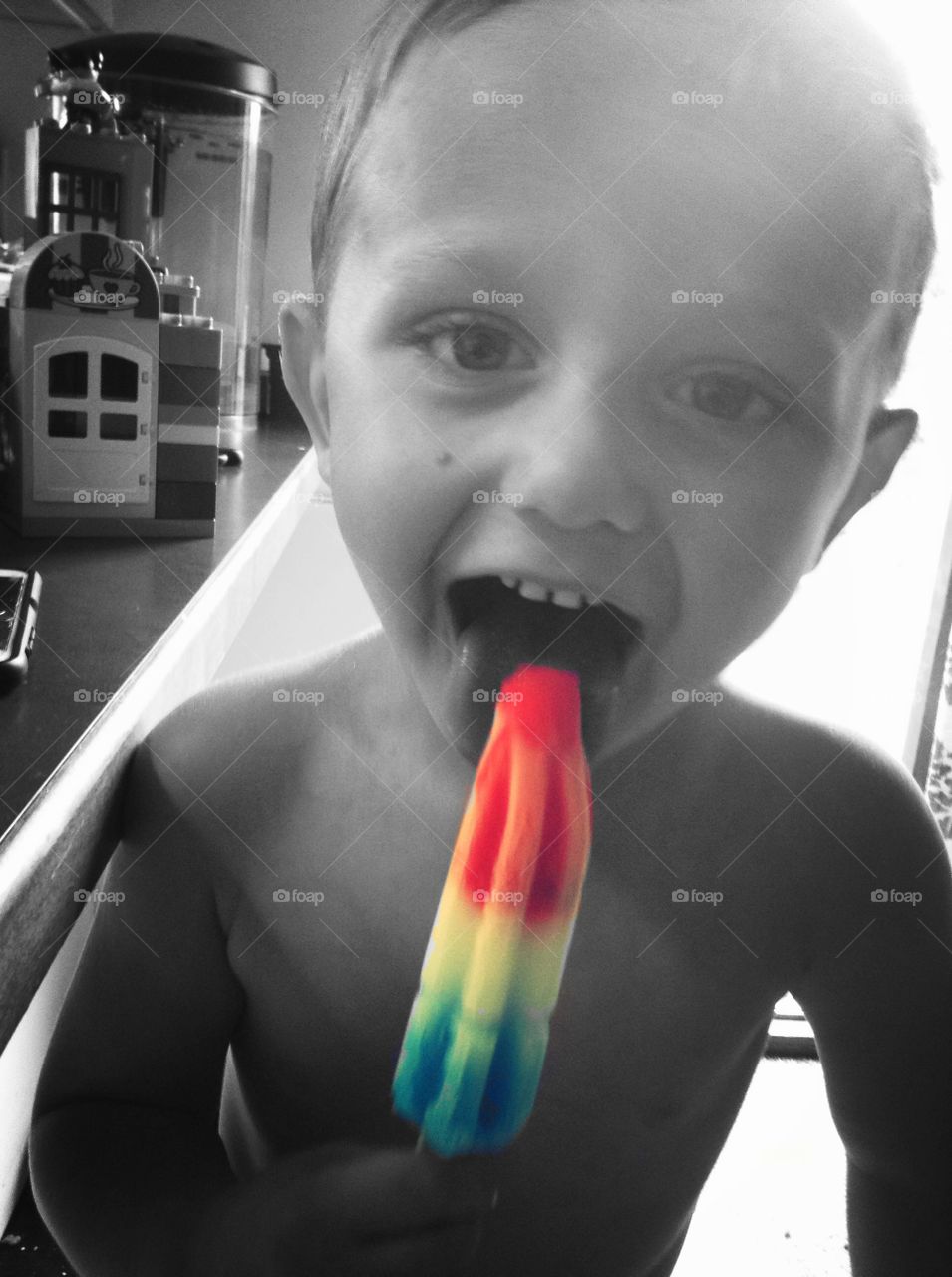 Cute boy licking popsicle ice at home