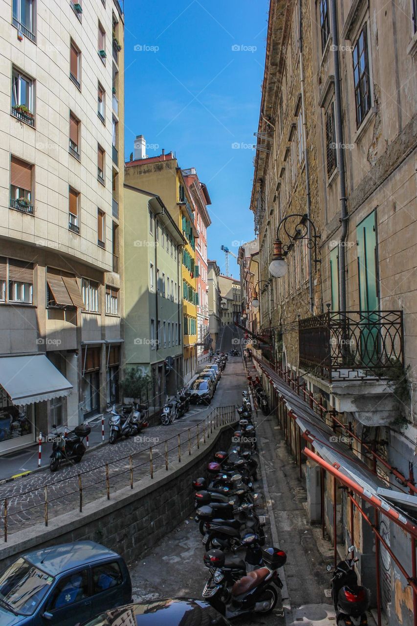 Scooters are parked on the street near the road.