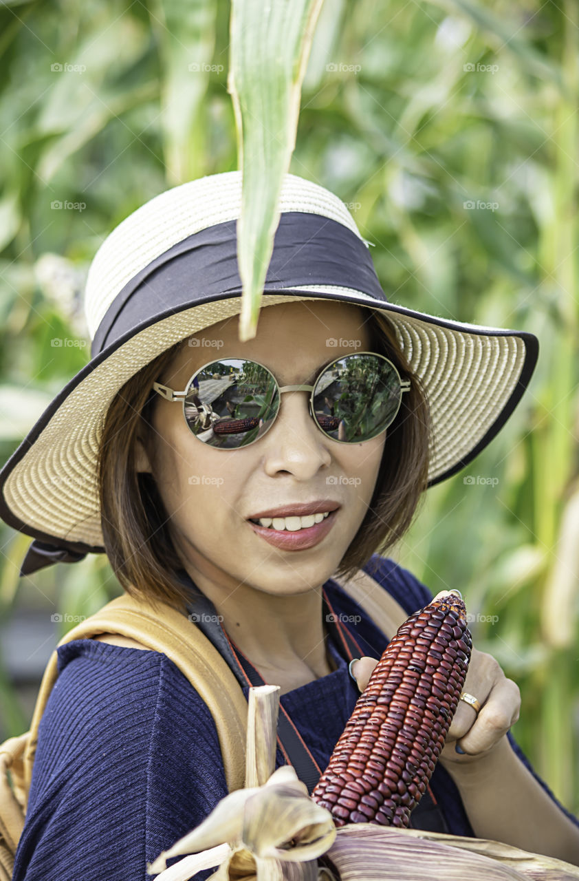 A woman holding the corn at the show in the farm.