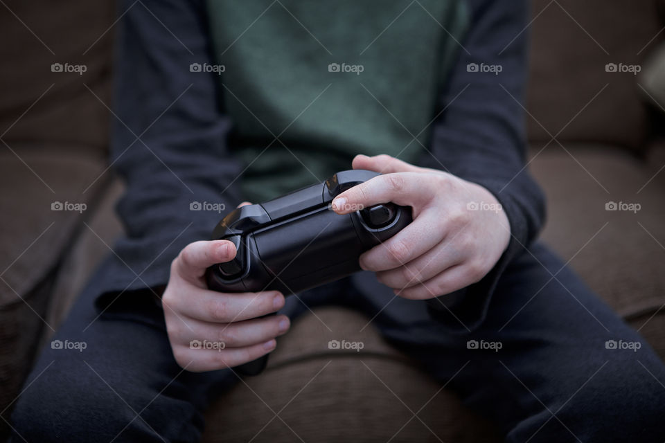 Young Caucasian boy playing video games hold game controller. 