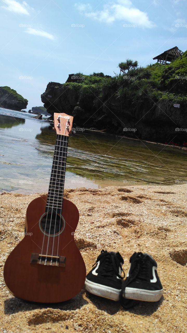 guitar and shoes on beach