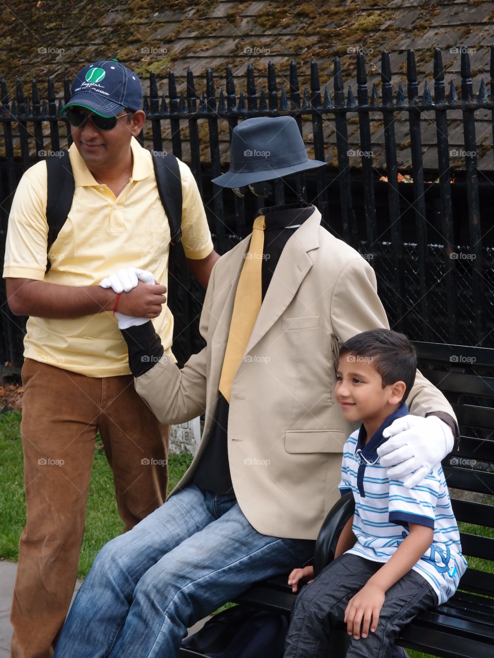 A young boy and his father pose in the park with an entertainer without a face on a summer day. 