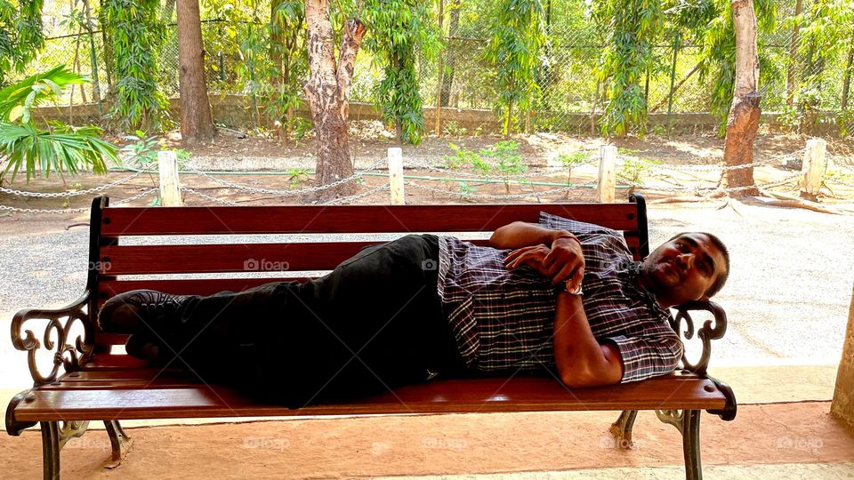 Man in relax mood take rest on bench this is a forest place natural place take pure oxygen