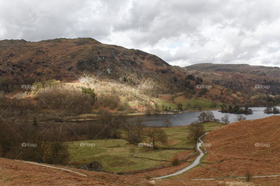 Mountain near river in Lake District in the UK, sunlight illuminating the mountain.