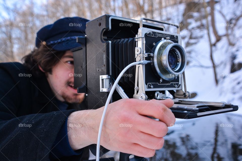 A man uses the old fashion photography equipment of a film camera to capture his image 