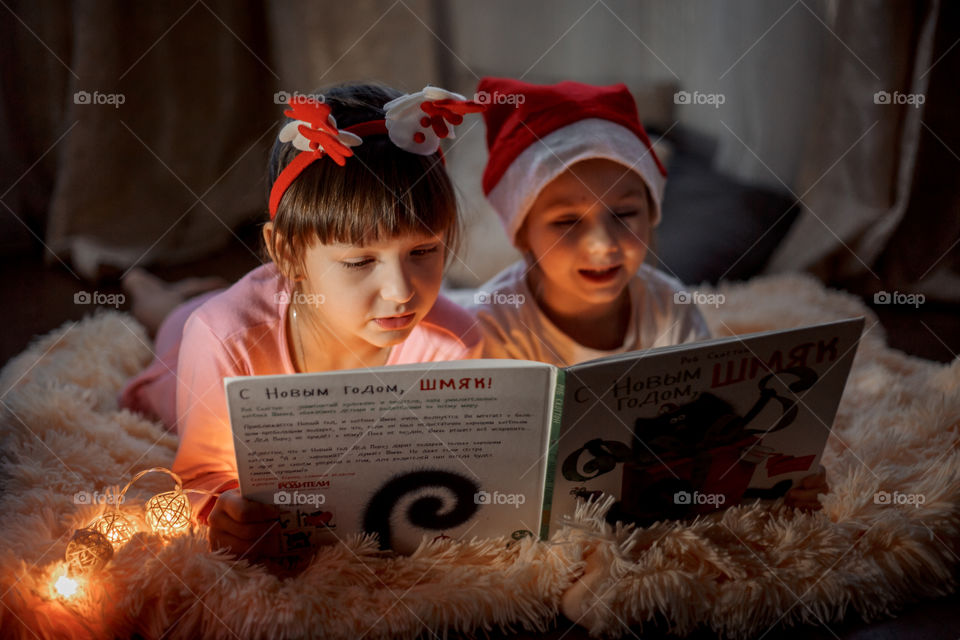 Little sisters reading a book at Christmas time 