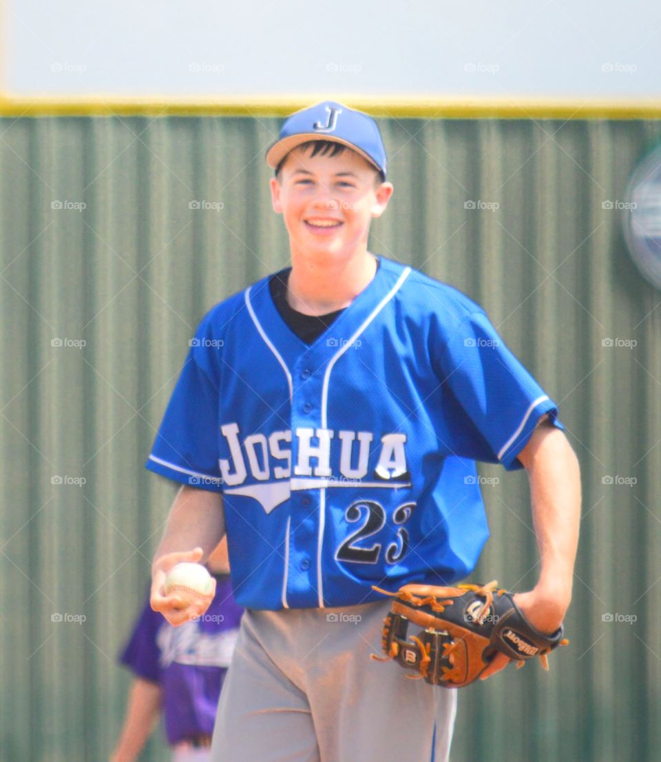 Teenager baseball pitcher holding ball with glove