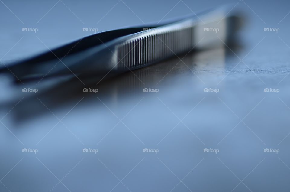 A pair of tweezers rest on a sterile tray in preparation for a surgical procedure in the operating room.