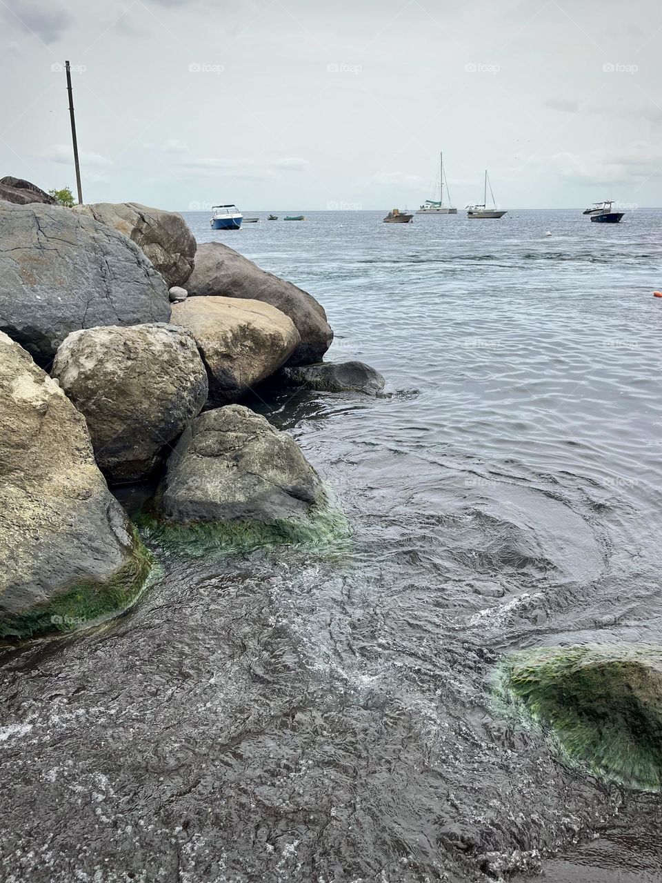 Rocky seaside of the Caribbean with boats moored in the background
