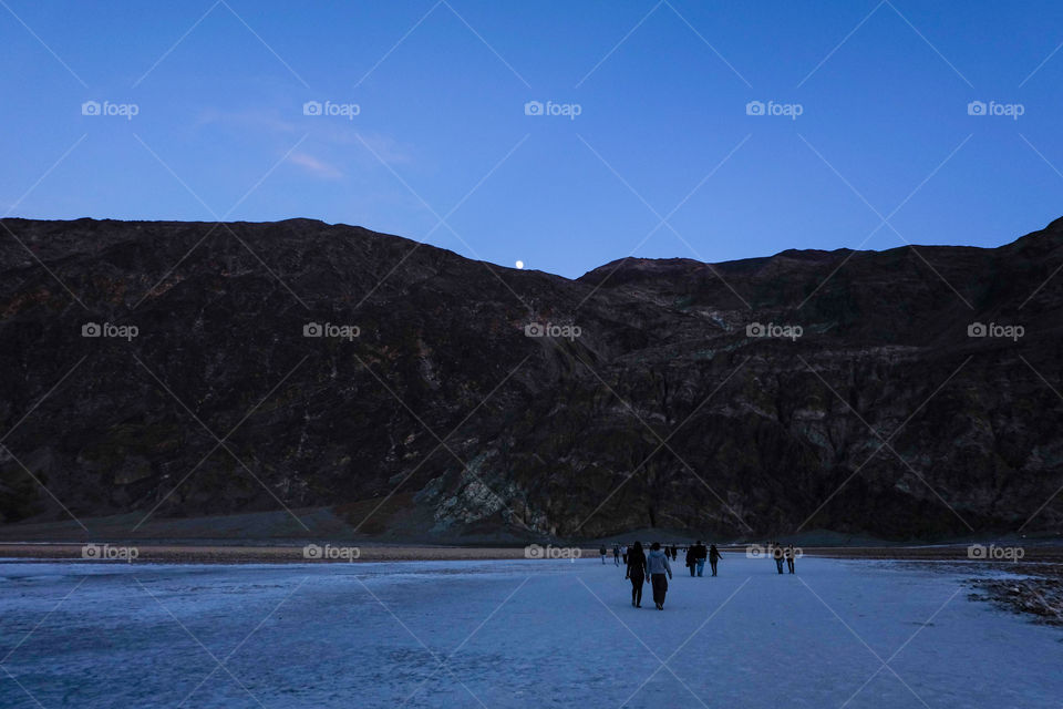 People enjoying moon rising from behind a hill