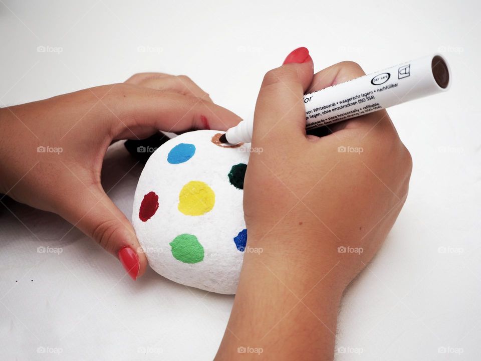 A girl is painting a stone in different colors