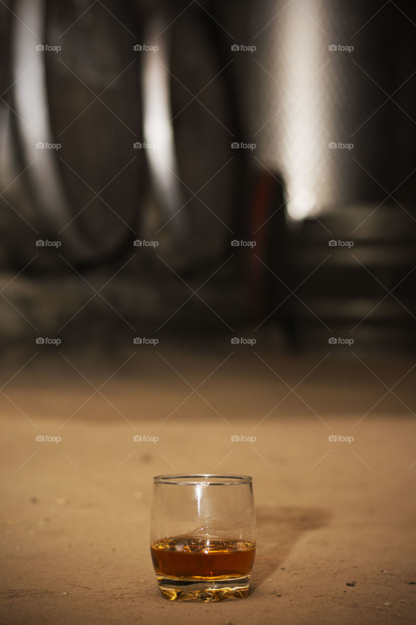 glass of whiskey on floor. glass of whiskey on floor among barrels in distillery