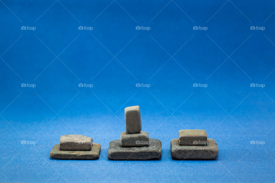 Symmetrical close up of square and rectangle shaped slate stones on a blue background.