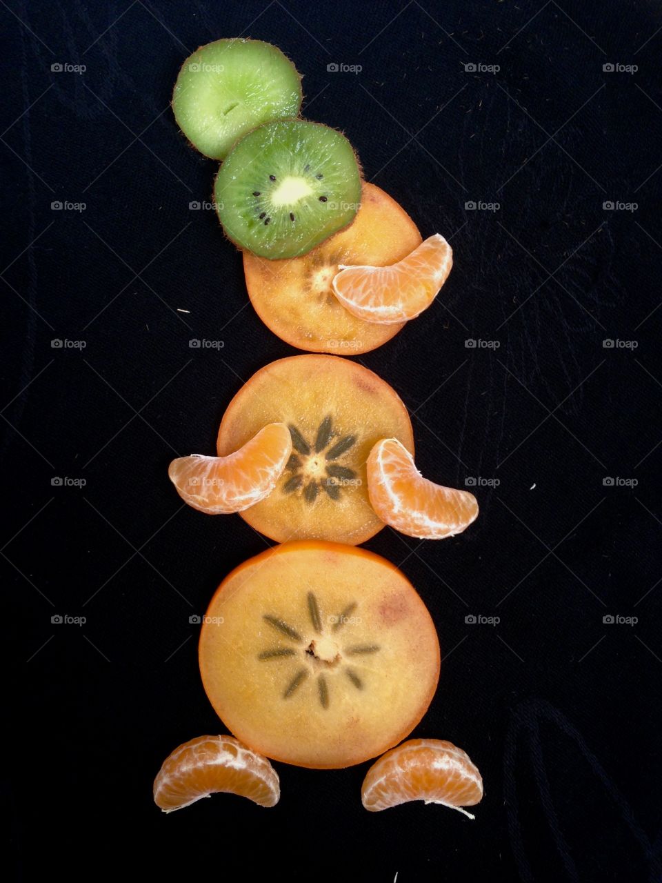 Snowman made with pieces of fruits isolated on black  