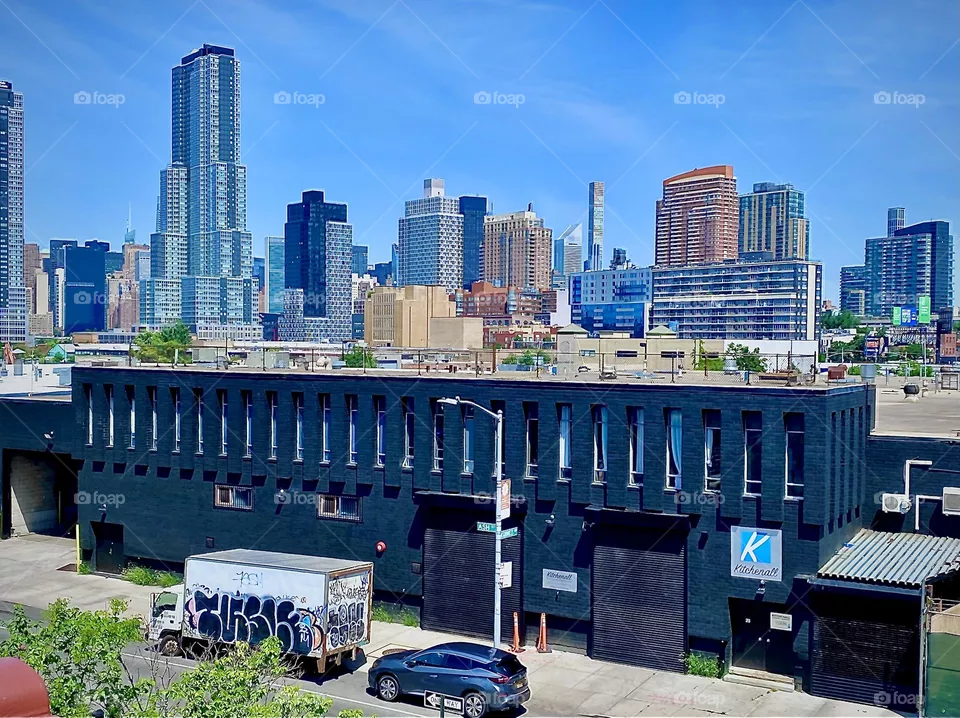 The skyline of LIC, Queens and way back in the furthest distance parts of the „Manhattan skyline“ can be seen from the staircase leading up to the pedestrian lane of the „Pulaski Bridge“ on the „Greenpoint“, Bklyn side. 2022. Hypnotic Productions