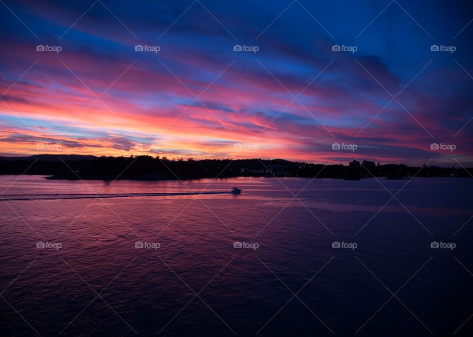 A beautiful sunset with gorgeous colors over beautiful water that has a delicate reflection with the soft colors of the sunset. 