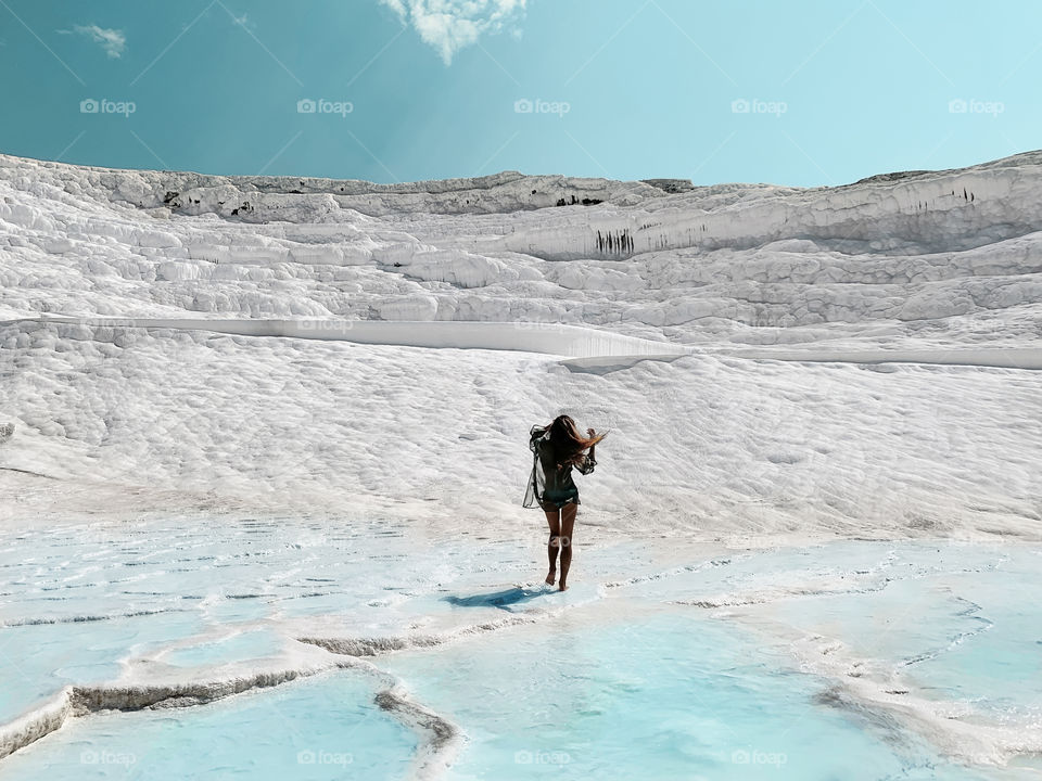 Tiny figure of a young woman walking by the white chalk mountain with blue lagoons 