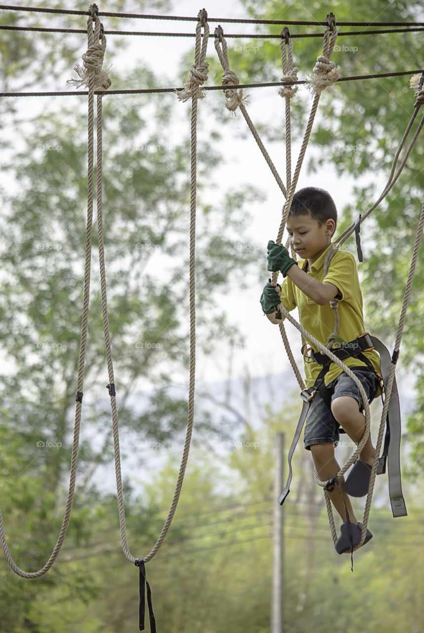 Asean boy nodes the rope and smiling happily background blurry tree.