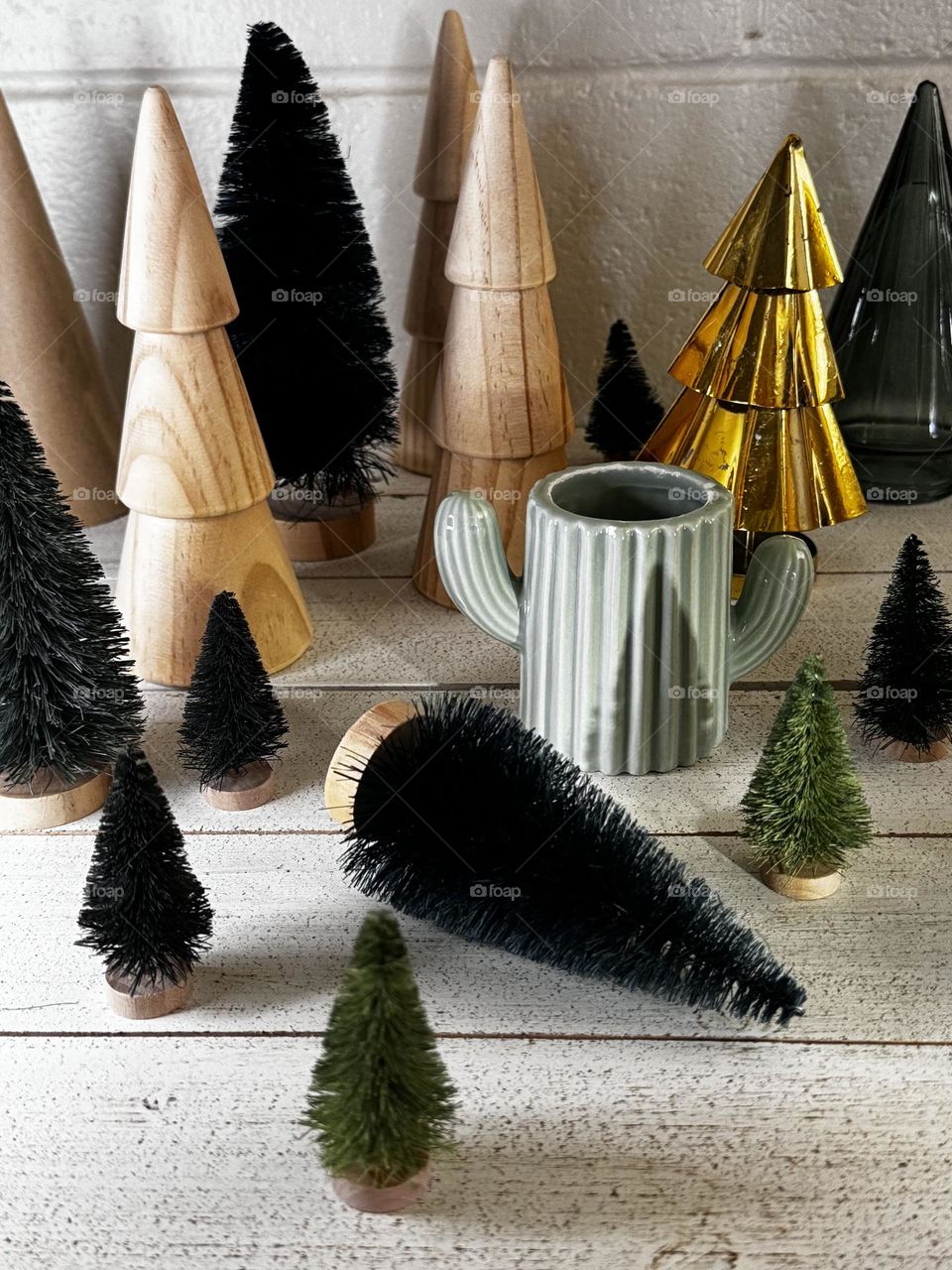 Christmas tree decorations made of wood paper sisal bristles glass and plated brass with ceramic cactus pot on whitewashed board