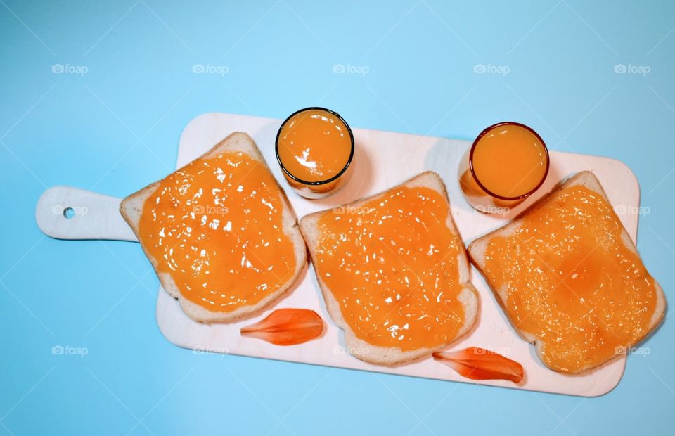 jam of Apricot on a slices of bread and nectar on a blue background