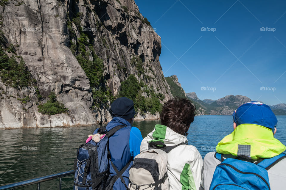 Challenge ahead. Back view at hikers admiring mountain rocks in fjord. Norway.