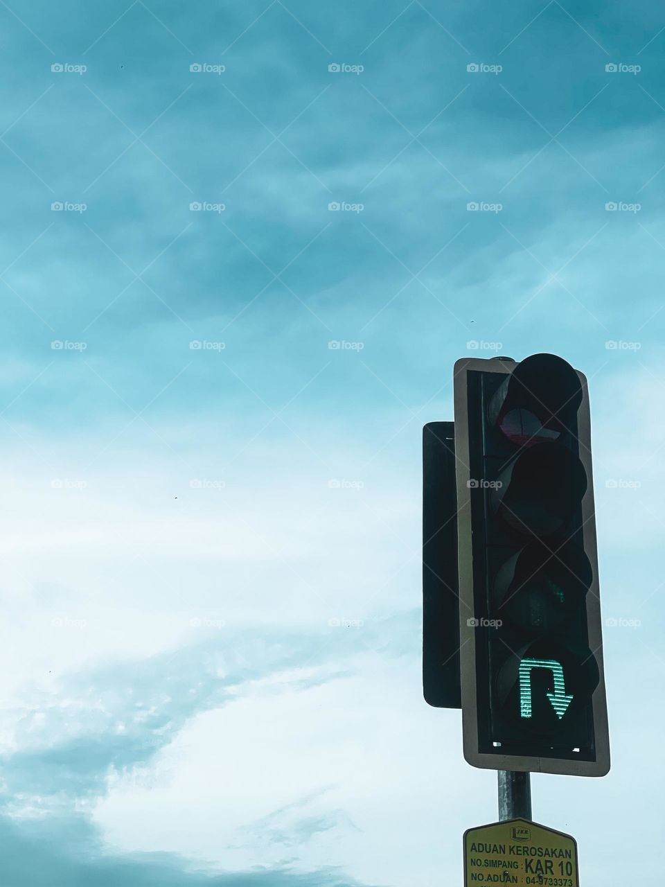 Close up view of a green traffic light with light clouds in the sky