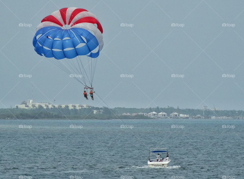 Parasailing In The Tropics. Adventurous Couple Parasailing Over The Caribbean
