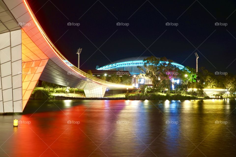 Adelaide oval footbridge and Adelaide oval stadium by night, reflections in the River Torrens. 