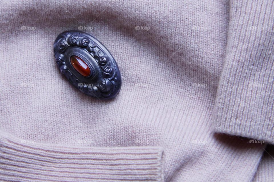 Close up of a small brooch on a lavender colored wool sweater