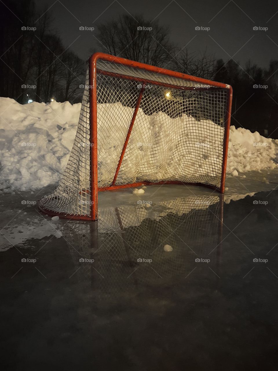 Ice hockey goal on a snowy bank with water on ice.
